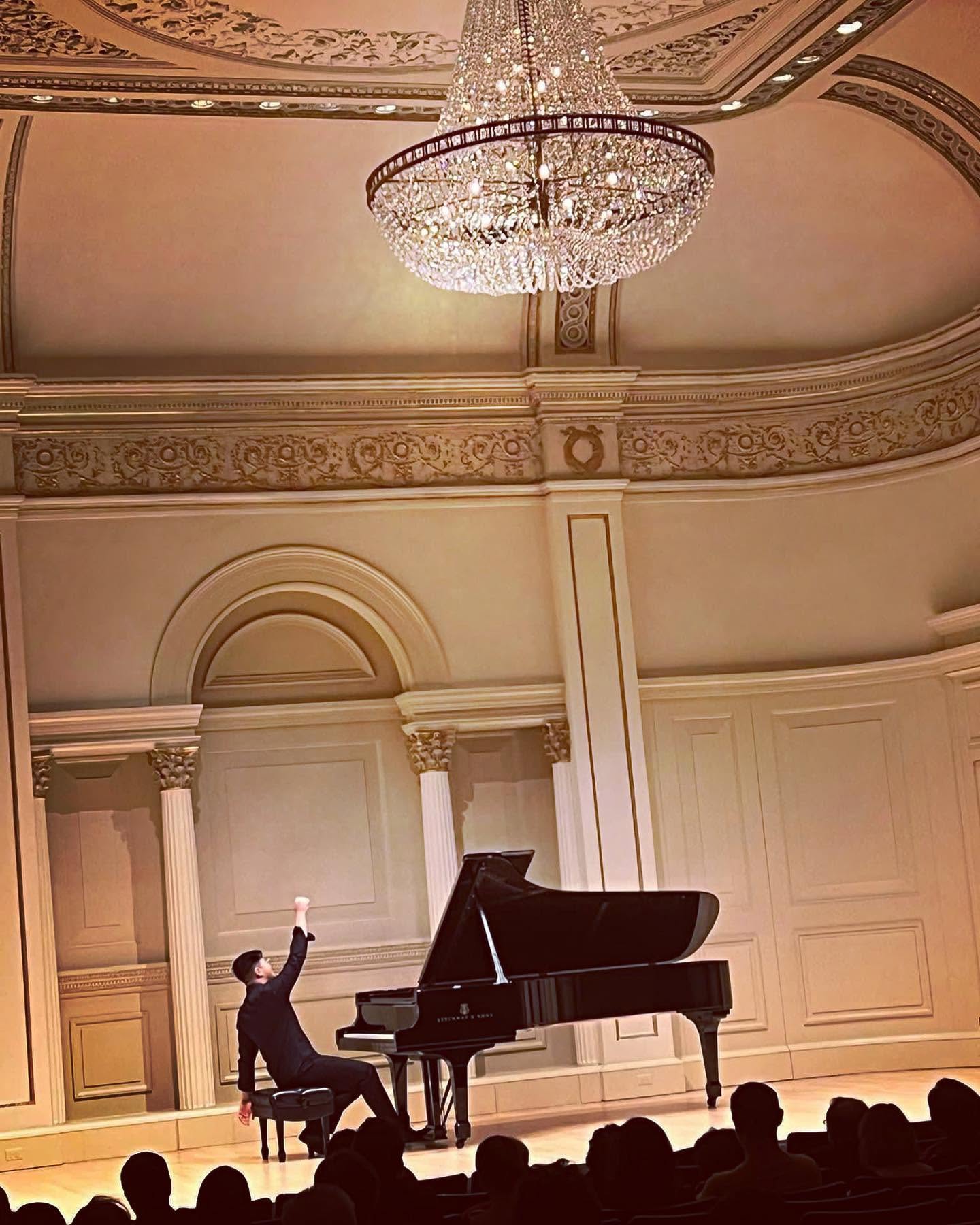 Stephen Joven-Lee acknowledging the audience beside a grand piano at Carnegie Hall